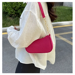 Side view of trendy hot pink shoulder bag with gold chain strap on female model