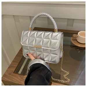 Detail of silver quilted handbag with braided handle and golden metallic chain strap