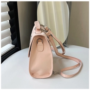 Side view of pale pink faux leather handbag with adjustable strap and silver hardware