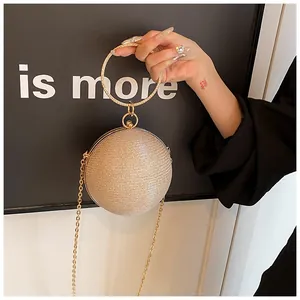 Macro view of gold spherical evening bag with textured glitter and metal ring handle