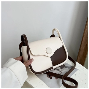 Close-up of retro color-block shoulder bag with cream and brown faux leather finish