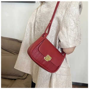 Detail of red quilted crossbody bag with golden rectangular lock on model