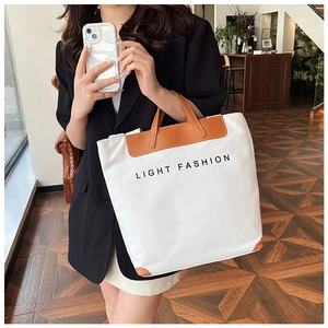 Detail of canvas tote bag with brown leather trim and Light Fashion text print