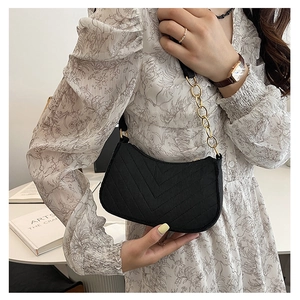 Detail of black V-quilted shoulder bag with elegant gold chain strap and zipper hardware