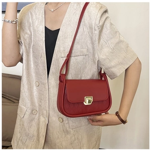 Detail of red quilted faux leather crossbody bag with elegant gold-tone square twist lock
