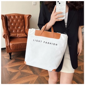 Detail of the large canvas tote bag featuring brown leather straps and Light Fashion text