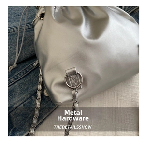 Detail view of silver bucket bag featuring metallic chain strap and drawstring closure