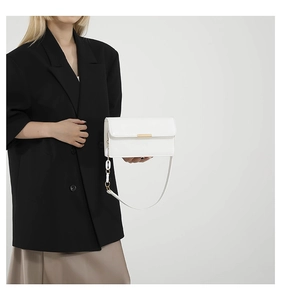Detail of white rectangle leather bag showing lychee texture and gold metal buckle