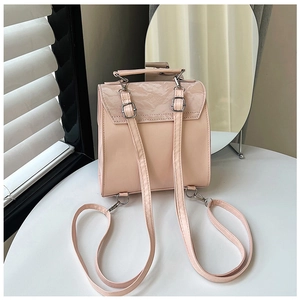 Detail of pink faux leather mini backpack with textured flap and silver metal buckles