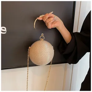 Close-up of champagne gold spherical evening bag with glitter texture and metal ring handle
