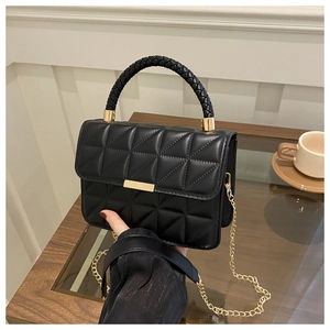 Close-up of quilted black crossbody bag with woven handle and gold metal hardware