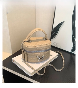 Detail of khaki mini box bag with quilted PU texture and silver butterfly ornament