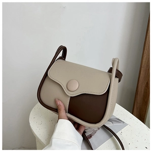 Close-up of a retro beige and brown crossbody bag showing fine stitching and round buckle