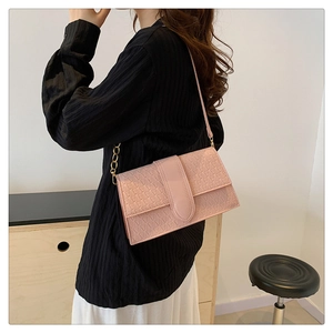 Detailed side view of pink geometric embossed flap bag with gold chain strap on model