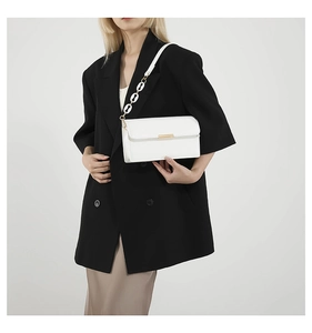 Detailed view of white rectangular crossbody bag with gold metal trim and chain strap