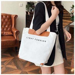 Detail of the reinforced brown leather corners and base on a white canvas tote bag