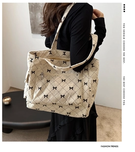 Detail of corduroy tote bag with black bow print and large front zipper pocket