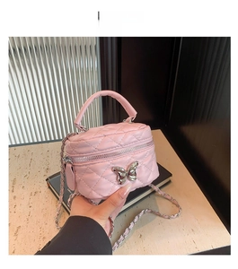 Detailed view of a pink quilted mini trunk bag with silver butterfly and chain strap