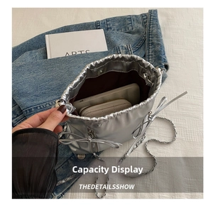 Interior capacity of silver ballet-style bucket bag with chain strap and bow detail