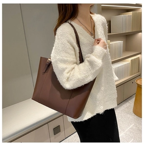 Brown PU leather tote bag with gold buckle detail shown on shoulder of a model