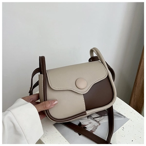 Close-up of contrast color crossbody bag with round button buckle and PU leather finish