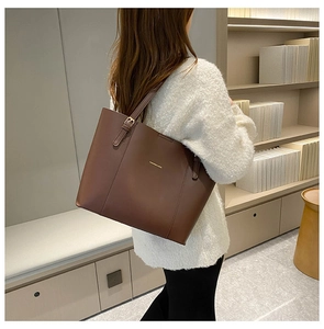 Detail of dark brown leather tote bag worn by a model in a cozy, elegant atmosphere