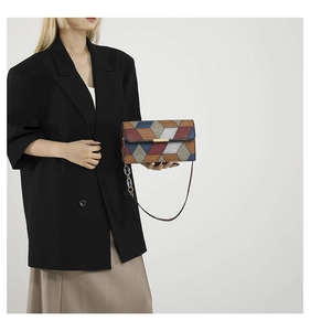 Detail of crossbody bag with geometric crocodile pattern and metal clasp closure