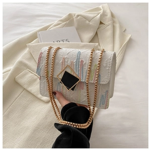 Detail of white chain bag featuring colorful embroidery and geometric metal buckle