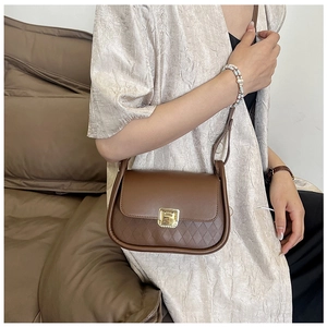 Detail view of brown leather crossbody bag with quilted pattern and gold square lock clasp