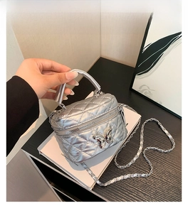 Close-up of a silver quilted mini box bag featuring a shiny metal butterfly buckle and chain