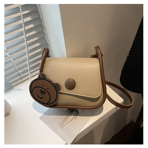 Vue détaillée du sac rétro en similicuir beige et marron avec son pendentif ours
