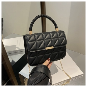 Detail of black quilted leather handbag with gold bar clasp and woven top handle strap