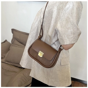 Close-up of brown crossbody bag with gold rectangular buckle and quilted texture