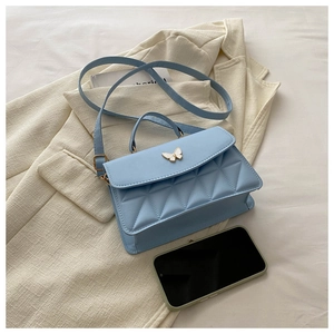 Detail of light blue quilted leather bag with a white enamel butterfly buckle