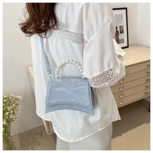 Detail of light blue wrinkled texture bag with pearl handle and signature curved base