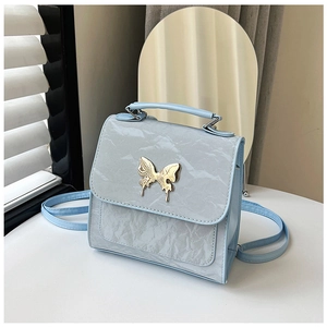 Close-up of light blue small square bag featuring pleated texture and gold butterfly clasp