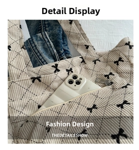Detail of corduroy tote bag showing bow embroidery and outer pocket for smartphone