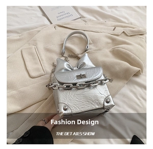 Detail van de zilveren metallic tas met grote strik en dikke metalen schakelketting