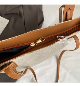Detailed macro view of smooth metal zipper and brown leather trim on canvas tote bag