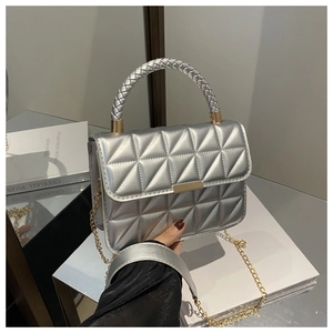 Detailed shot of silver quilted handbag with woven handle and gold hardware detail