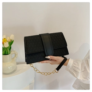 Detail of black leather handbag with 3D triangle embossing and gold chain strap