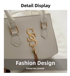Detailed view of the gold interlocking S logo and fringe pendant on white square handbag