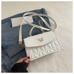 Detail der weißen Stepptasche mit Schmetterlingsverschluss auf Denim-Hintergrund