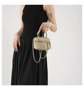 Detail of beige quilted mini handbag with metal butterfly buckle and chain strap