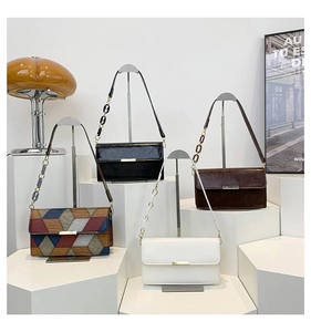 Close-up of stylish contrast color leather bag with marble resin chain and gold buckle
