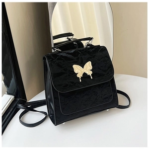 Detail of black wrinkled texture bag with golden lava-style butterfly metal buckle