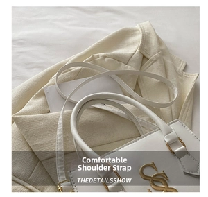 Detail of white leather handbag with golden metal logo and premium detachable shoulder strap