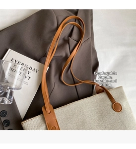 Detail of minimalist canvas tote with brown leather handles on a brown blazer backdrop