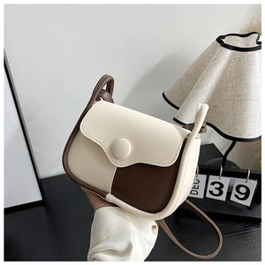Detail of two-tone beige and coffee shoulder bag with round clasp and textured finish
