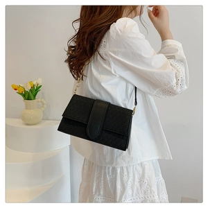 Detail of black crossbody bag featuring geometric triangle pattern and gold chain strap